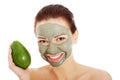 Beautiful woman with facial mask holding avocado. Royalty Free Stock Photo