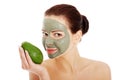 Beautiful woman with facial mask holding avocado. Royalty Free Stock Photo