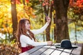 Beautiful woman in fall forest park taking selfie self photo.