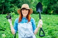 Beautiful woman farmer holds a bunch of basil and shovel in a straw hat and surrounded by the many plants in her vegetable garden Royalty Free Stock Photo