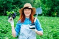 Beautiful woman farmer holds a bunch of basil and shovel in a straw hat and surrounded by the many plants in her vegetable garden Royalty Free Stock Photo