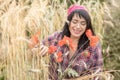 A beautiful woman farmer 40 years old rejoices in the harvest of wheat in the field among the ears and poppies. Summer time,