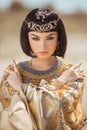 Beautiful woman with fashion make-up and hairstyle like Egyptian queen Cleopatra outdoors against desert