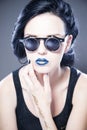 Beautiful woman fashion model portrait in sunglasses with blue lips and earrings. Creative hairstyle and make up