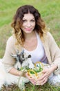 Beautiful woman is feeding a small goat grass