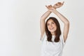Beautiful woman feeling free and happy, raising hands up and smiling, standing over white background