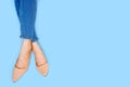 Beautiful Woman Feet & Slim Legs in Beige Medium High Heels on Pastel Blue. Portrait of Legs. Young Female Wearing Jeans Royalty Free Stock Photo