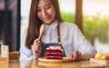 A beautiful woman, female chef baking and eating a piece of red velvet cake in wooden tray Royalty Free Stock Photo