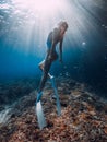 Beautiful woman with fins glide underwater in blue sea. Freediving with sporty girl in ocean and sun rays Royalty Free Stock Photo