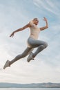 Beautiful woman fitness instructor jumps on the sky background Royalty Free Stock Photo