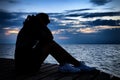 Beautiful woman in frustrated depression sitting on wooden bridge, near the beach on sunset. Concept Royalty Free Stock Photo