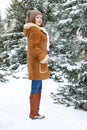 Beautiful woman full length on winter outdoor, snowy fir trees in forest, long red hair, wearing a sheepskin coat Royalty Free Stock Photo