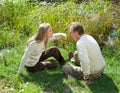 The beautiful woman for fun threatens to knock the man on a nose in the summer on a grass at the lake