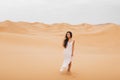 Beautiful woman in gentle silk dress walking sand dunes of Morocco Sahara desert