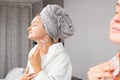 Beautiful woman is getting massage face using jade roller in front of the mirror at home Royalty Free Stock Photo