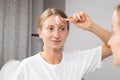 Beautiful woman is getting massage face using jade roller in front of the mirror at home Royalty Free Stock Photo