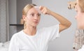 Beautiful woman is getting massage face using jade stone in front of the mirror at home Royalty Free Stock Photo