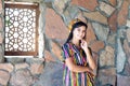 Beautiful woman, girl in national folk Uzbekistan dress against stone wall and ancient window background Royalty Free Stock Photo