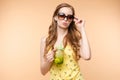 Beautiful smiling Asian woman in summer outfit with a glass of orange juice isolated on colorful yellow background Royalty Free Stock Photo