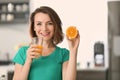 Beautiful woman with glass of healthy citrus juice and orange half in kitchen Royalty Free Stock Photo
