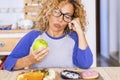 Beautiful woman with glasses choosing green apple of donuts - healthy and sane lifestyle concept