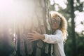 Beautiful woman with glasses hugging a big tree with love and affection - save the forest concept and lifestyle - adult at the Royalty Free Stock Photo