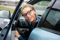 Beautiful woman in glasses looks back over her shoulder as she exits a parked car in which she drove Royalty Free Stock Photo