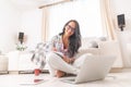 Beautiful woman in glasses smiling with a tilted head while sitting on the living room floor working on a pc and notepad Royalty Free Stock Photo