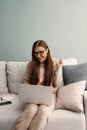 Beautiful woman in glasses using laptop for remote work. Young female working with laptop sitting on couch.Online shoping, Payment Royalty Free Stock Photo
