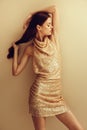 Beautiful woman in a gold sequined dress poses in a stylish look for a Christmas disco night party. High quality photo