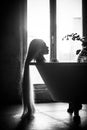 A beautiful woman with gorgeous long blond hair is relaxing in the bath. Silhouette of a woman in profile lying in the bathroom Royalty Free Stock Photo