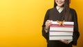 Beautiful woman in graduation gown is holding books and certificate on yellow background Royalty Free Stock Photo