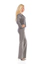 Beautiful Woman In Gray Suit Is Standing With Hand On Hip. Side View. Royalty Free Stock Photo