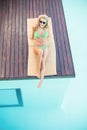 Beautiful woman in green bikini relaxing by pool side Royalty Free Stock Photo