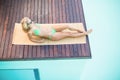 Beautiful woman in green bikini relaxing by pool side Royalty Free Stock Photo