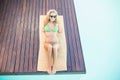 Beautiful woman in green bikini relaxing by poolside Royalty Free Stock Photo