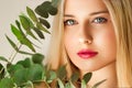 Beautiful woman and green leaves branch, blonde hair, red lipstick make-up face portrait, natural beauty and cosmetics Royalty Free Stock Photo
