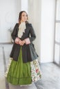 Beautiful woman in green medieval dress and frock-coat near wind