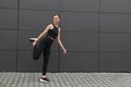 Beautiful woman in gym clothes doing exercises near dark grey wall on street, space for text Royalty Free Stock Photo