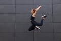 Beautiful woman in gym clothes jumping near dark grey wall on street, space for text Royalty Free Stock Photo