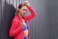 Beautiful woman in gym clothes posing near dark grey fence on street, space for text Royalty Free Stock Photo