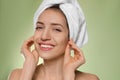 Beautiful woman with hair wrapped in towel after washing on light green background Royalty Free Stock Photo