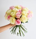 Beautiful woman hand hold bouquet of yellow and pink roses flowers on white Royalty Free Stock Photo