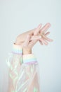 Beautiful woman hands and arms wearing a sweater with holographic effect, modern avantgarde artificial plastic look