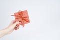 Woman hand holding red gift with ribbon, manicured hand with nail polish on white background with copy space Royalty Free Stock Photo