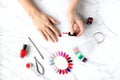 Beautiful woman hands painting nails with red nail polish on marble table with manicure set on it. Royalty Free Stock Photo