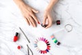 Beautiful woman hands painting nails with red nail polish on marble table with manicure set on it. Royalty Free Stock Photo