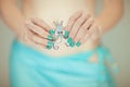 Beautiful woman hands with perfect blue nail polish holding little octopus brooch, happy bikini beach mood