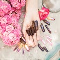 Beautiful woman hands with perfect violet nail polish on white wooden background holding little quartz crystals