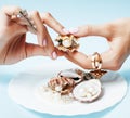 Beautiful woman hands with pink manicure holding plate with pearls and sea shells, luxury jewelry concept